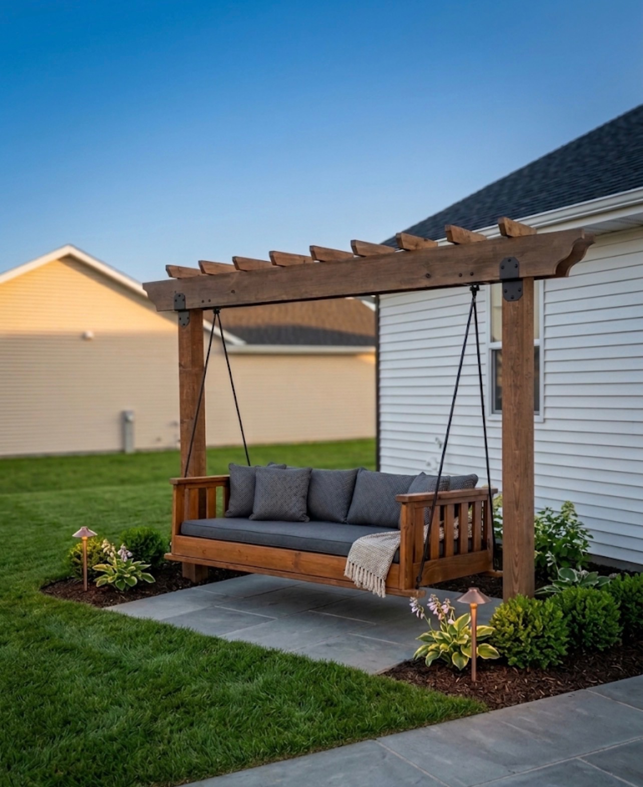Cedar pergola swing bed with charcoal cushions on a bluestone patio
